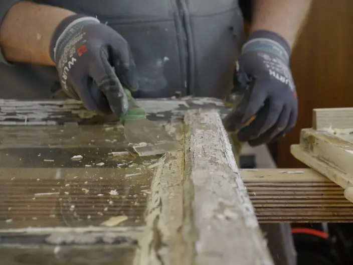 Alte Farbe an einem historischen Fenster entfernen
